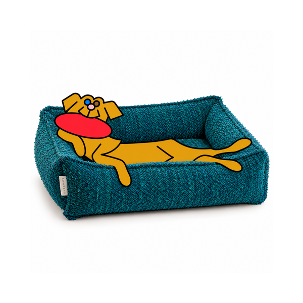 Bowsers Urban Lounger dog bed in teal with the illustrated Fetch dog reclining against the bolster, holding a red frisbee.
